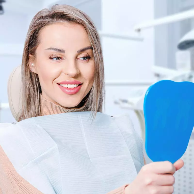 attractive woman looking at her teeth at All Smiles Dentistry in Miami Gardens